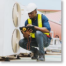 HVAC technician working on a roof mounted compressor.