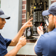 Electrical student learning about the circuit breaker box from an instructor.
