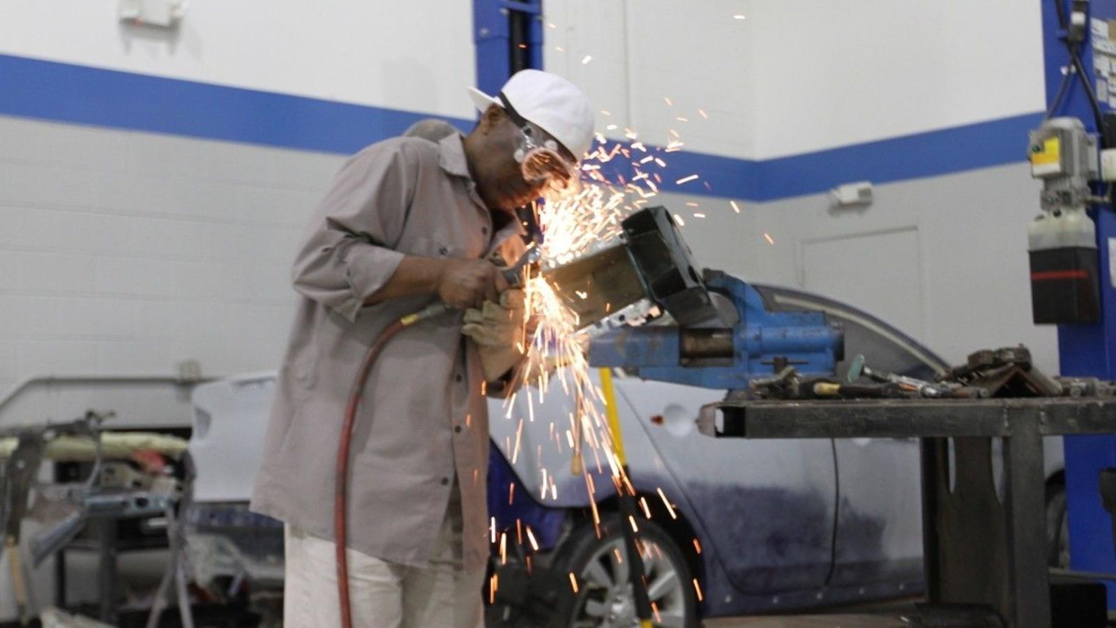 Close-up image of a collision student learning to use a pneumatic cutting wheel