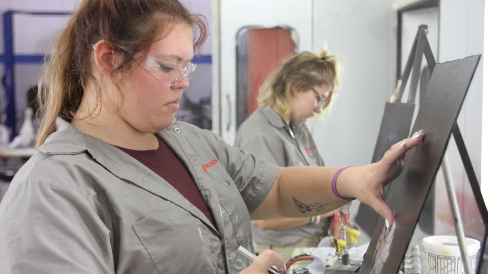 Two collision students practice air brushing techniques on spare panels.
