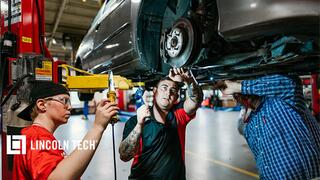 Auto tecnician students working with instructor under a car.