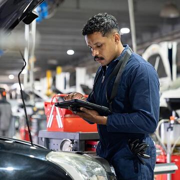 Auto technician with computer in garage.